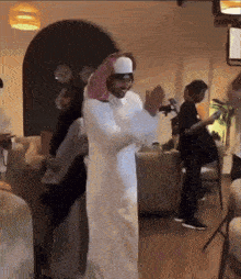 a man in a white robe is dancing in front of a camera