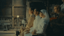 a woman in a white veil sits next to a man in a brown suit