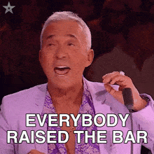 a man in a purple suit says everybody raised the bar in front of a microphone