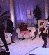 a group of people are sitting in a living room with purple lights