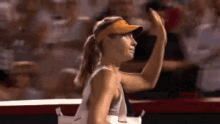 a woman wearing a visor is giving a high five while standing on a tennis court .