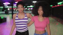 two women are rollerblading on a rink together