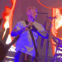 a man in a white shirt is playing a guitar and singing into a microphone