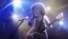 a girl is playing a guitar and singing into a microphone on stage .