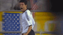 a soccer player is celebrating a goal in front of an american flag on a field .