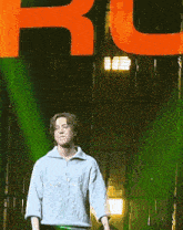 a man stands on a stage in front of a large orange letter r