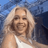a woman is sticking her tongue out while wearing a white tank top and a necklace .