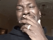 a man with a ring on his finger is covering his mouth with his hands .