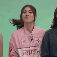a young woman wearing a pink ferrari jersey is making a funny face .
