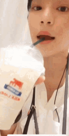 a woman is drinking milk from a plastic cup with a straw in her mouth .