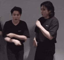 two men in black shirts are standing next to each other and making funny faces .