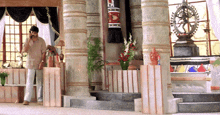a man talking on a cell phone in a room with columns and a statue