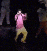 a boy in a pink shirt is dancing on a stage