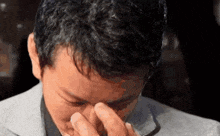 a man in a suit is covering his eyes with his hand