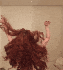 a woman with red hair and a tattoo on her arm throws her hair up in the air