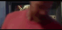 a close up of a person 's hand holding a red object in front of a television .
