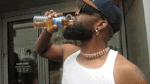 a man is drinking from a bottle in front of a west half building