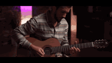 a man is playing an acoustic guitar with a striped shirt on