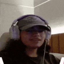 a woman wearing headphones and a hat is smiling for the camera .