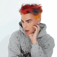 a man with red and yellow hair is wearing a gray hoodie