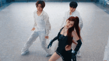 a woman in a black dress is surrounded by two men in white
