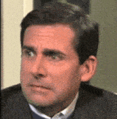 a man in a suit and tie is making a funny face while looking at the camera .