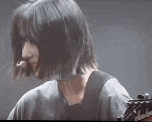 a woman with short hair is playing a guitar .