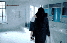 two women are walking in a bathroom with a sign that says ' laundry ' on it