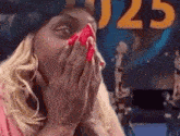 a woman with red nails is covering her face with her hands in front of a sign that says 025 .