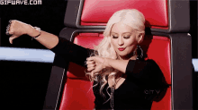 a woman is sitting in a red chair with a gifwave.com watermark
