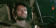 two men are sitting in a car talking to each other and one of them is smiling .