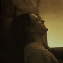 a man leaning against a wall with his head turned to the side
