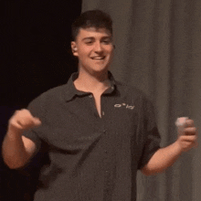 a young man in a black striped shirt is standing on a stage and smiling .