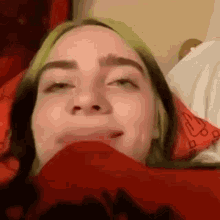 a close up of a person 's face with a red blanket covering her mouth .