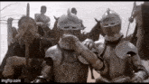a group of knights in armor are standing next to each other in front of a horse .