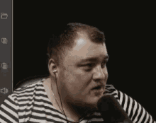 a man wearing ear buds and a striped shirt is speaking into a microphone