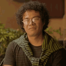 a man with curly hair wearing glasses and a green scarf