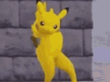 a yellow pikachu is dancing in front of a wall .