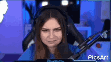 a woman wearing headphones and a blue shirt is sitting in front of a microphone and making a funny face .