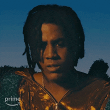 a man with dreadlocks is wearing a brown jacket with a zipper