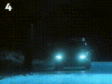 a car is driving down a snowy road at night with the number 4 visible in the sky