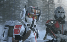 a couple of soldiers standing next to each other in a snowy forest .