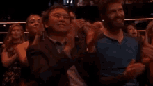 a group of people are sitting in a stadium clapping .