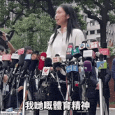 a woman stands in front of a bunch of microphones with one that says tmhk