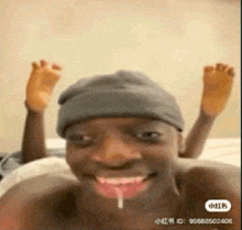 a man wearing a beanie is laying on a bed with his feet up and making a funny face .