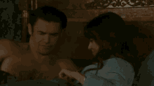 a man and a woman are laying on a bed and the man is smiling