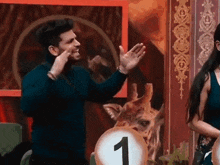 a man and a woman are standing next to each other in front of a giraffe with the number 1 on it .