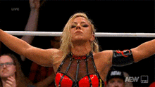 a woman is standing in a ring with her arms outstretched in front of a crowd .