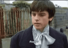 a young boy wearing a tie and a jacket is talking to someone .