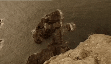a cliff overlooking a body of water with rocks in the water